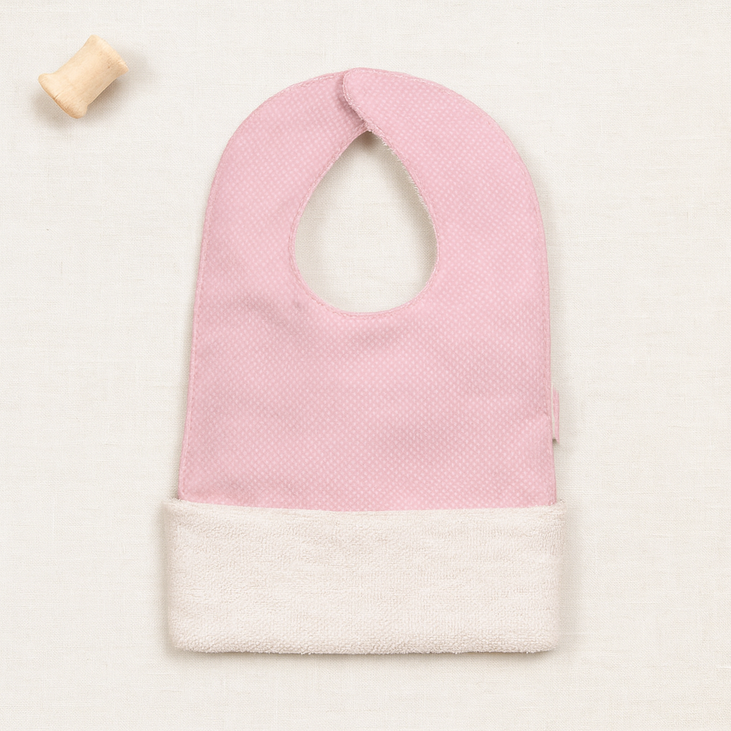 Babete de bebé rosa e creme com bobina de madeira
