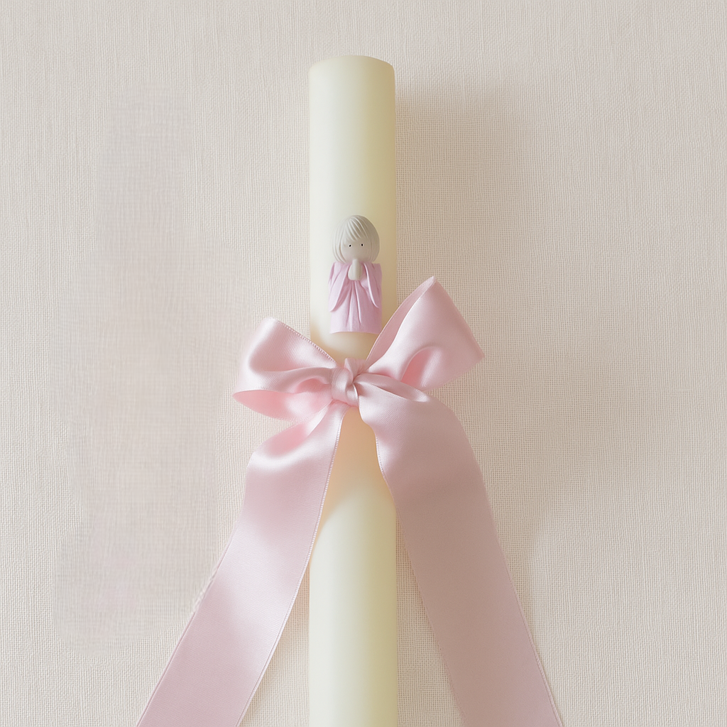 Vela branca decorada com anjo rosa e fita cor-de-rosa amarrada em laço