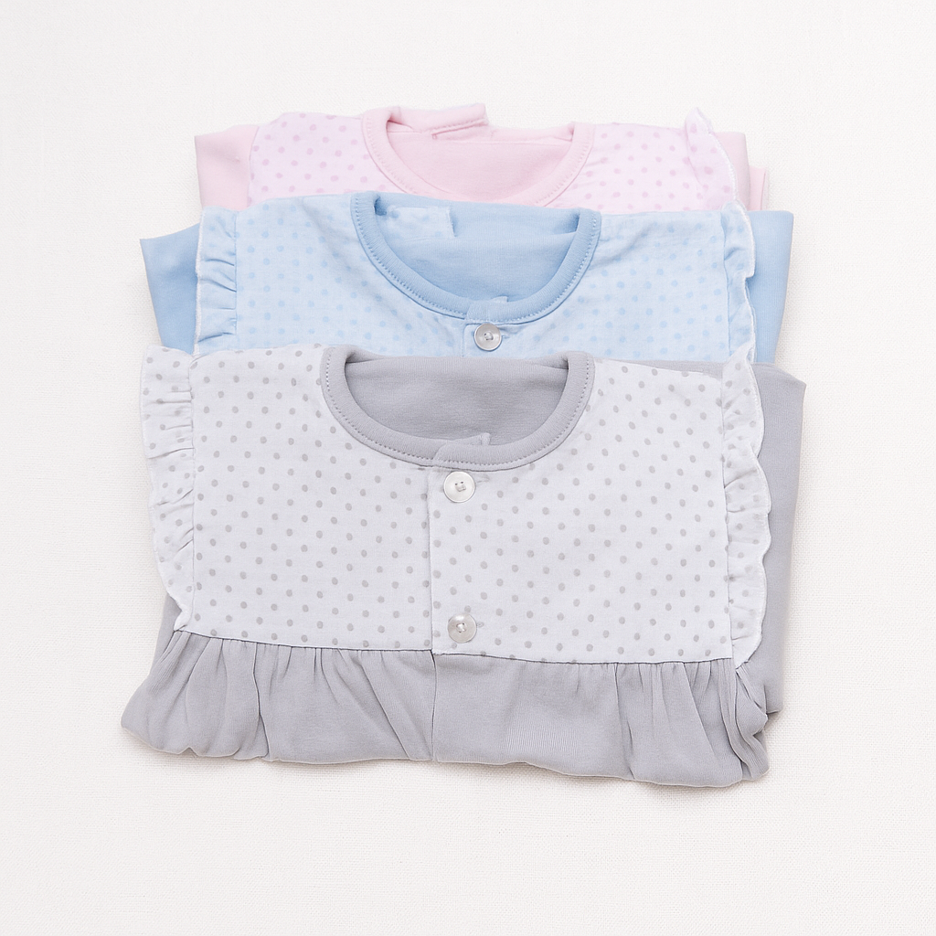 Peúgas de bebé rosa, azul e cinza com bolinhas empilhadas sobre fundo branco