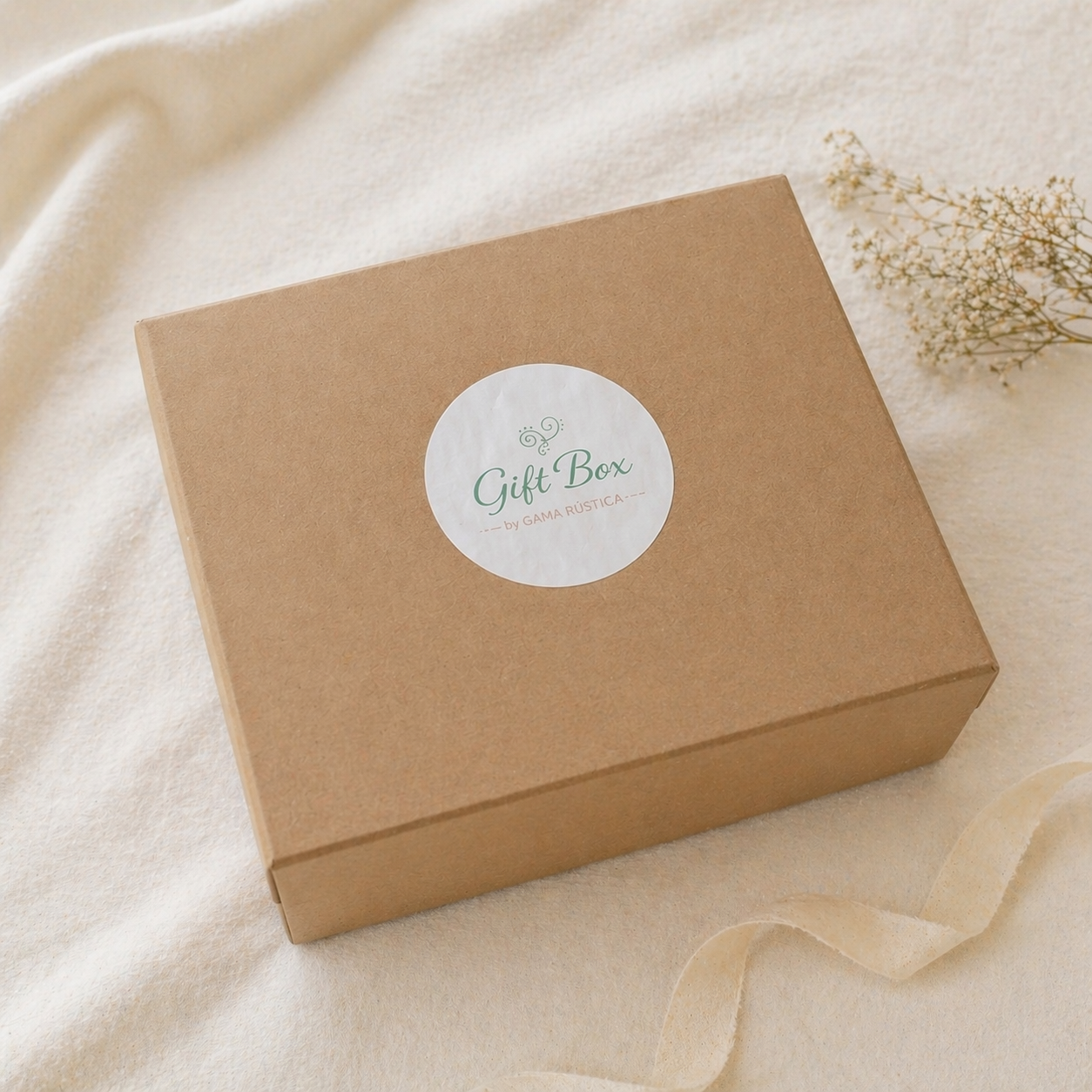 Caixa de presente castanha em cartão com etiqueta branca sobre tecido creme com flores e fita