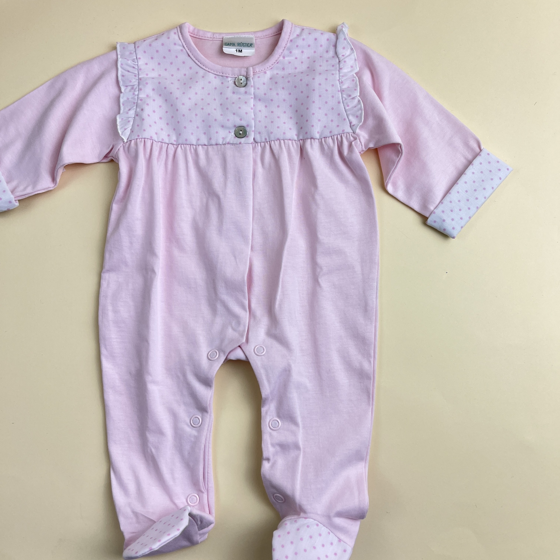 Pijama de bebé cor-de-rosa com padrão de pequenos pontos lilás e botões de pressão