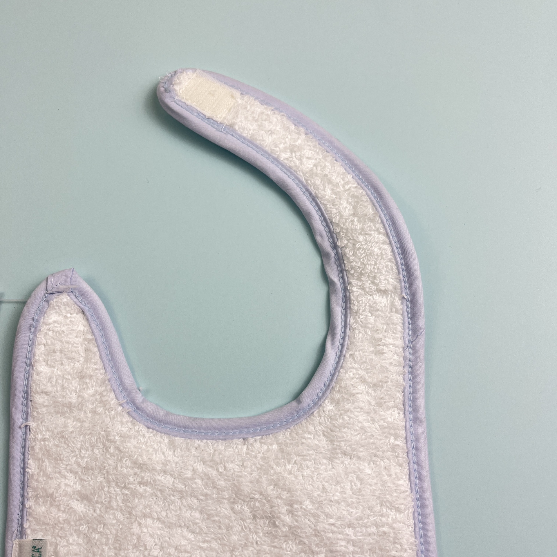 Babete de tecido branco com borda lilás