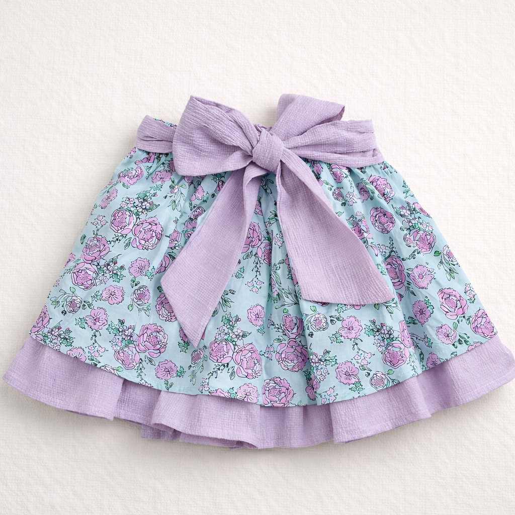 Saia infantil azul claro com padrão floral lilás e laço lilás grande texturizado