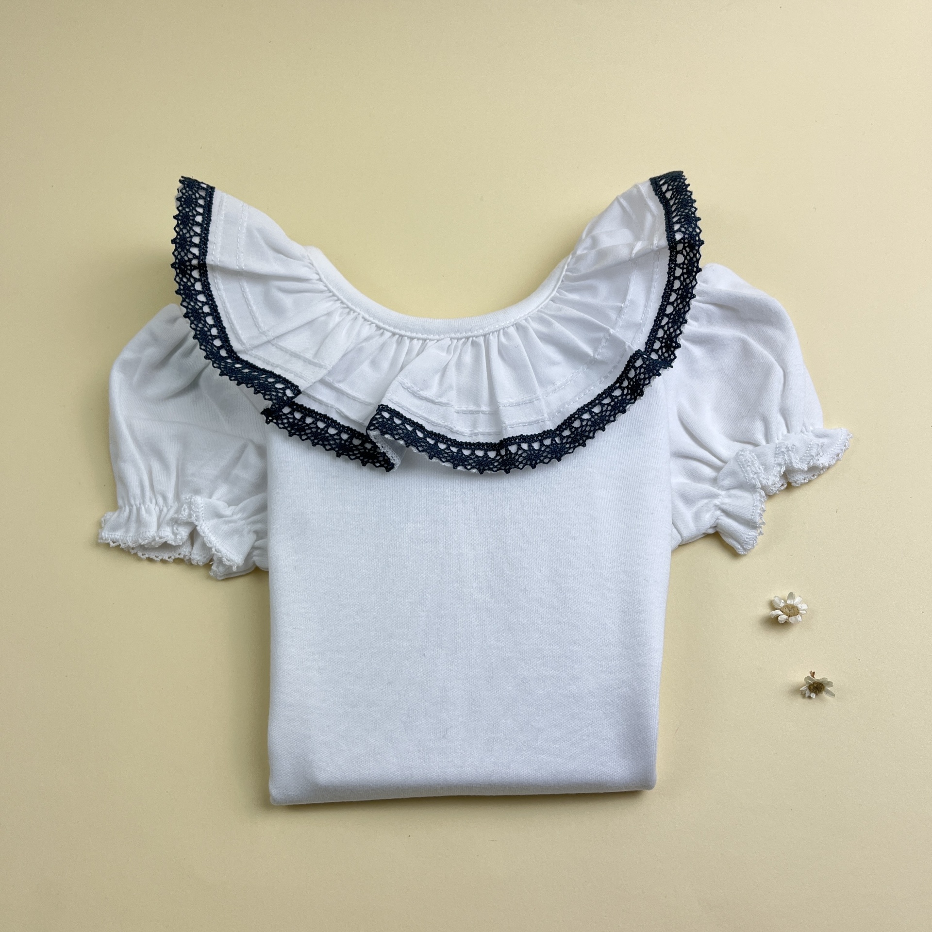 Camisola branca de manga curta com gola decorada e dois brincos pequenos ao lado