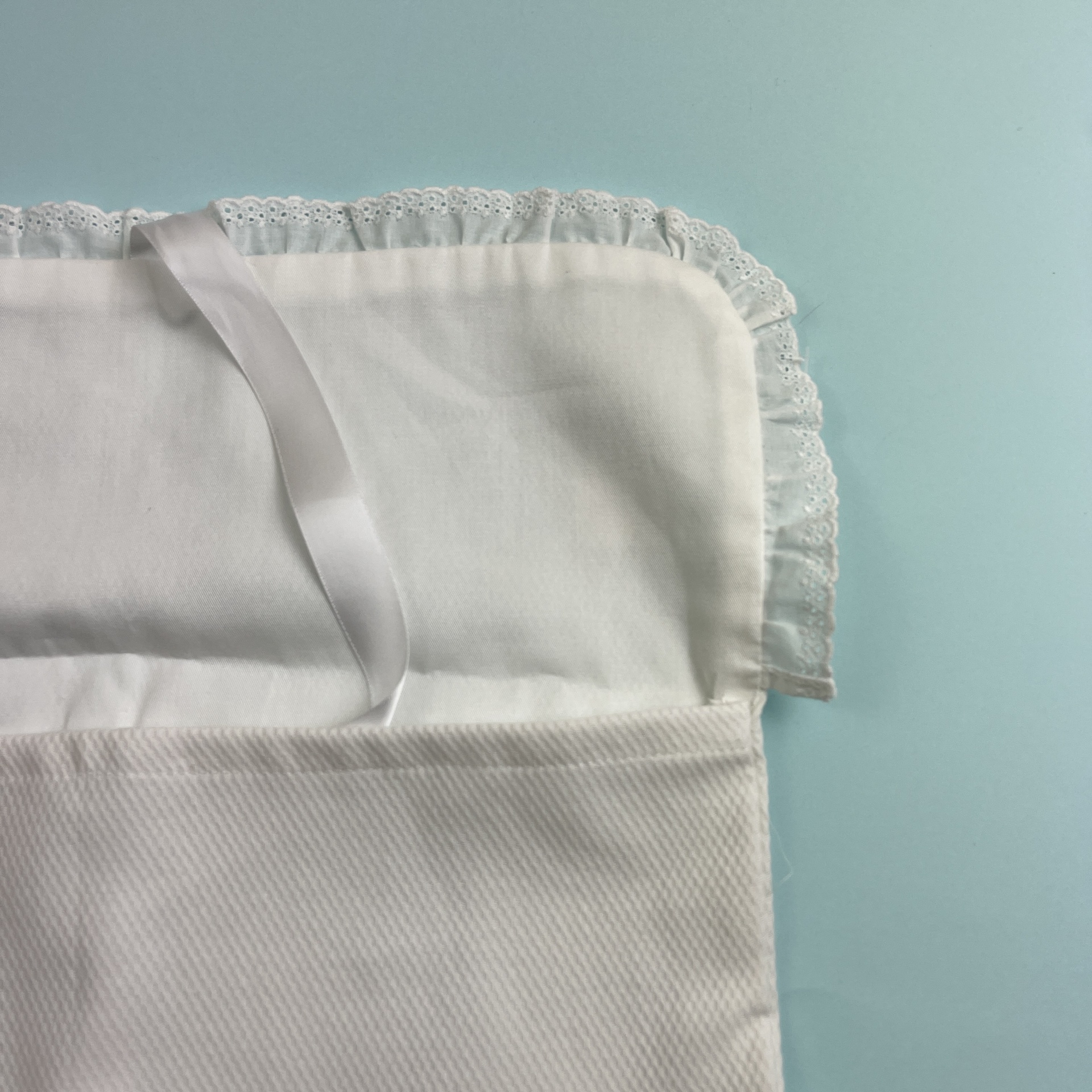 Envelope branco de tecido com renda e fita sobre fundo azul claro