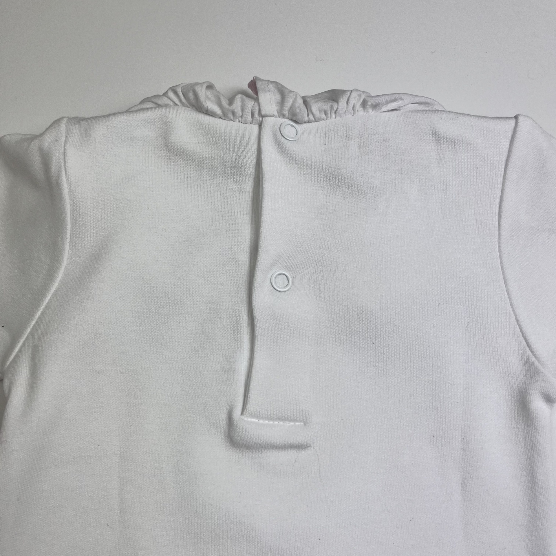 Roupa branca com botões e gola franzida vista de costas