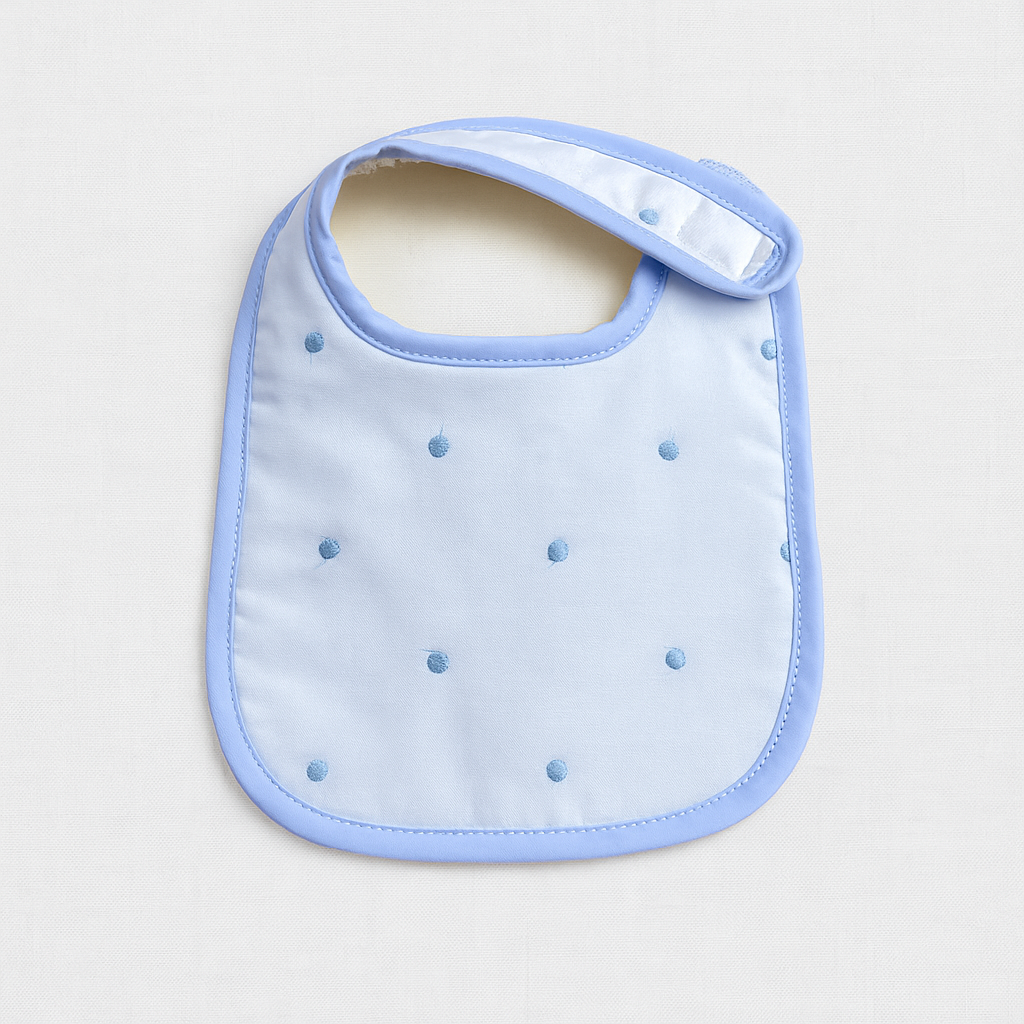 Babete azul claro com pontos bordados em azul escuro e fecho velcro