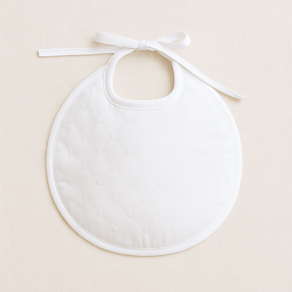 Babete redondo branco acolchoado com padrão de losangos e laço para amarrar