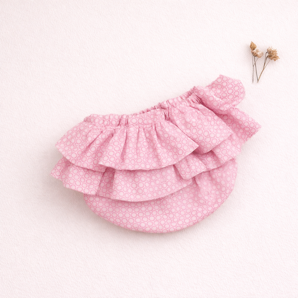 Saia rosa com padrão de círculos e folhos sobre fundo rosa claro