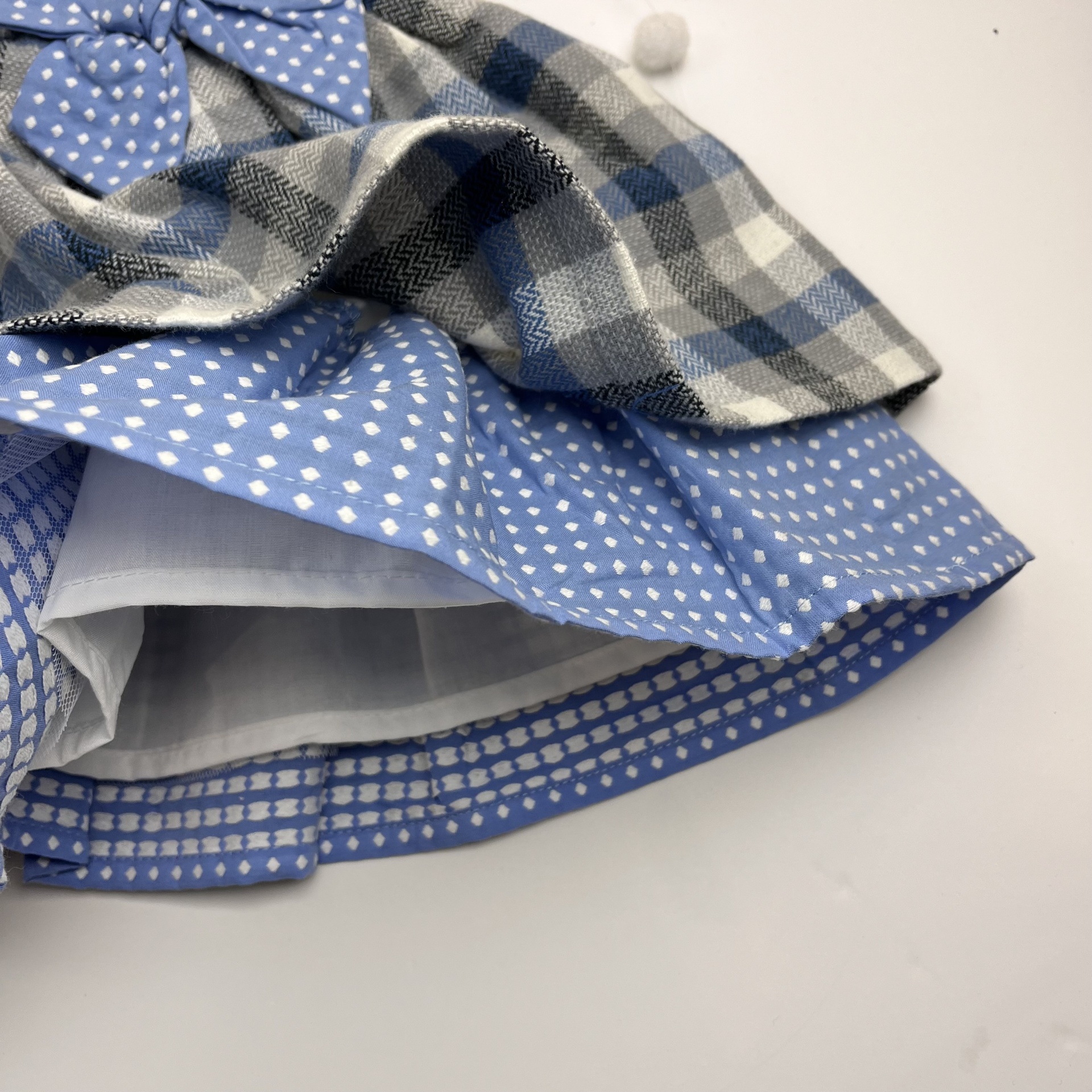 Saia com padrões xadrez cinza, corações brancos sobre azul claro e pontos brancos sobre azul escuro