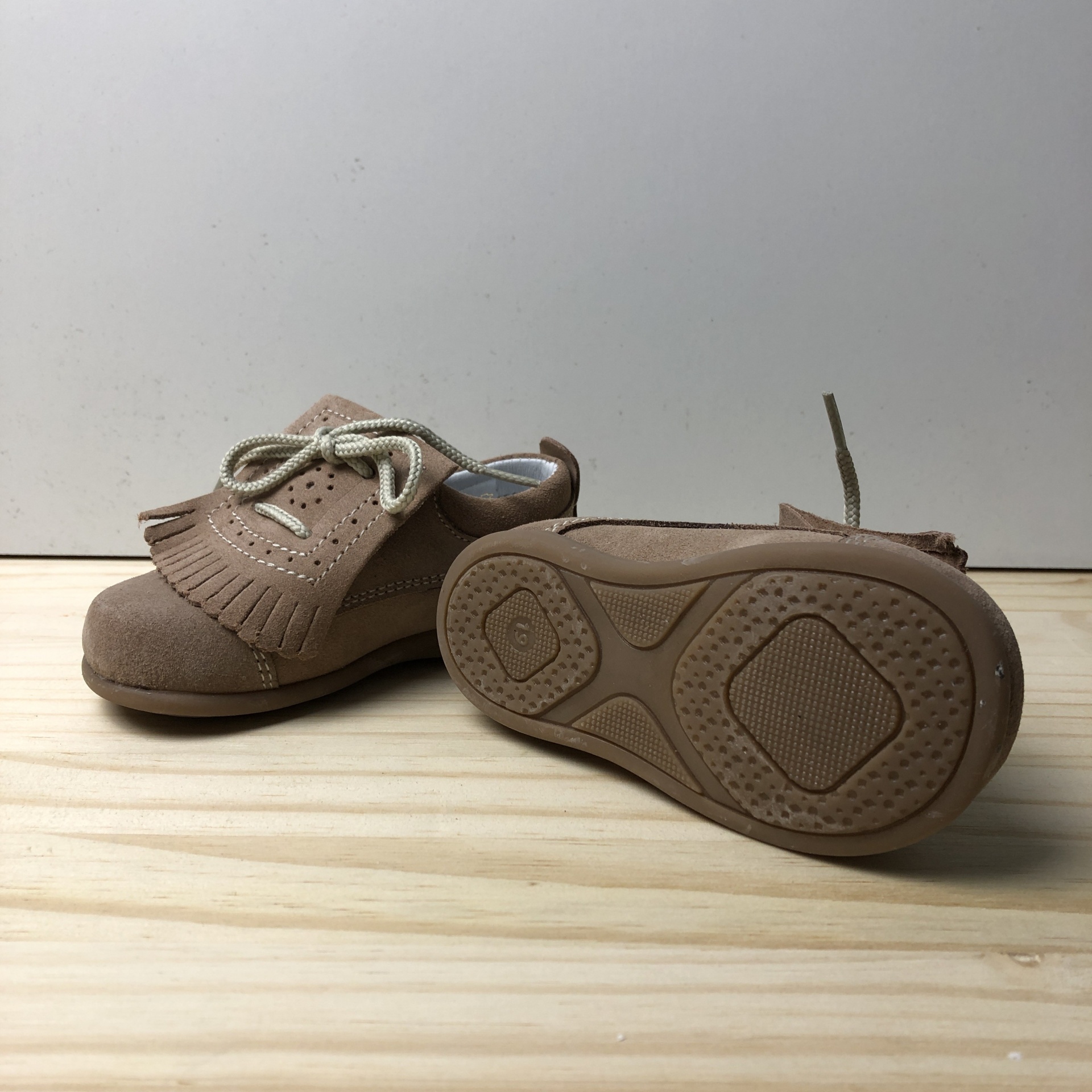 Sapatos infantis em camurça castanha clara com detalhes de franjas e atacadores brancos