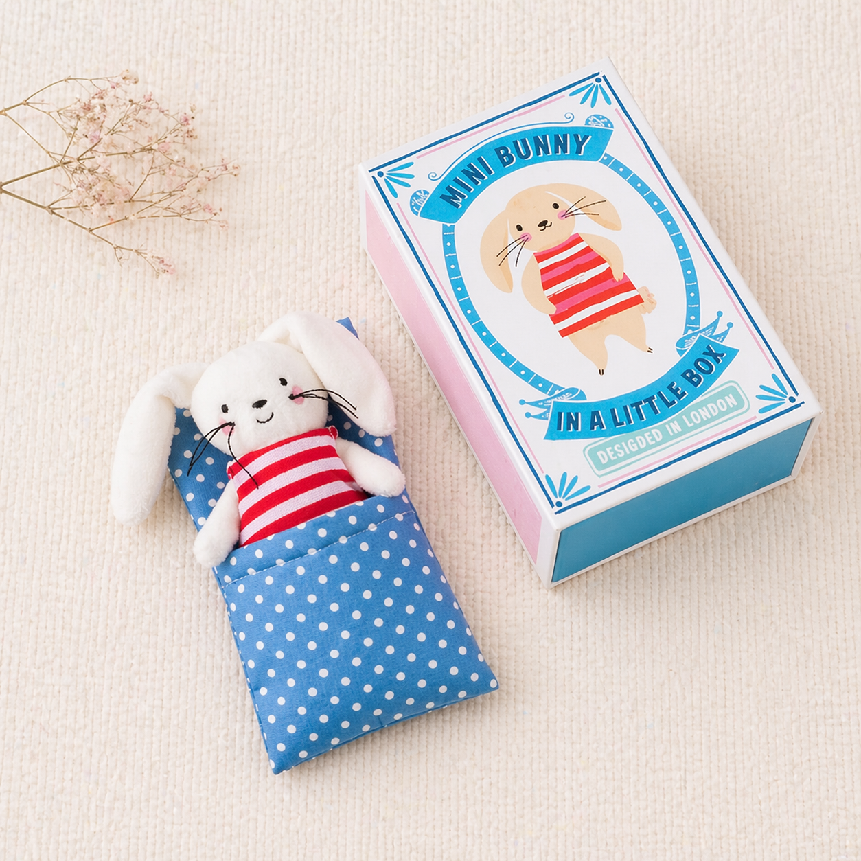 Mini peluche de coelho numa almofada azul com pontos brancos e caixa decorada