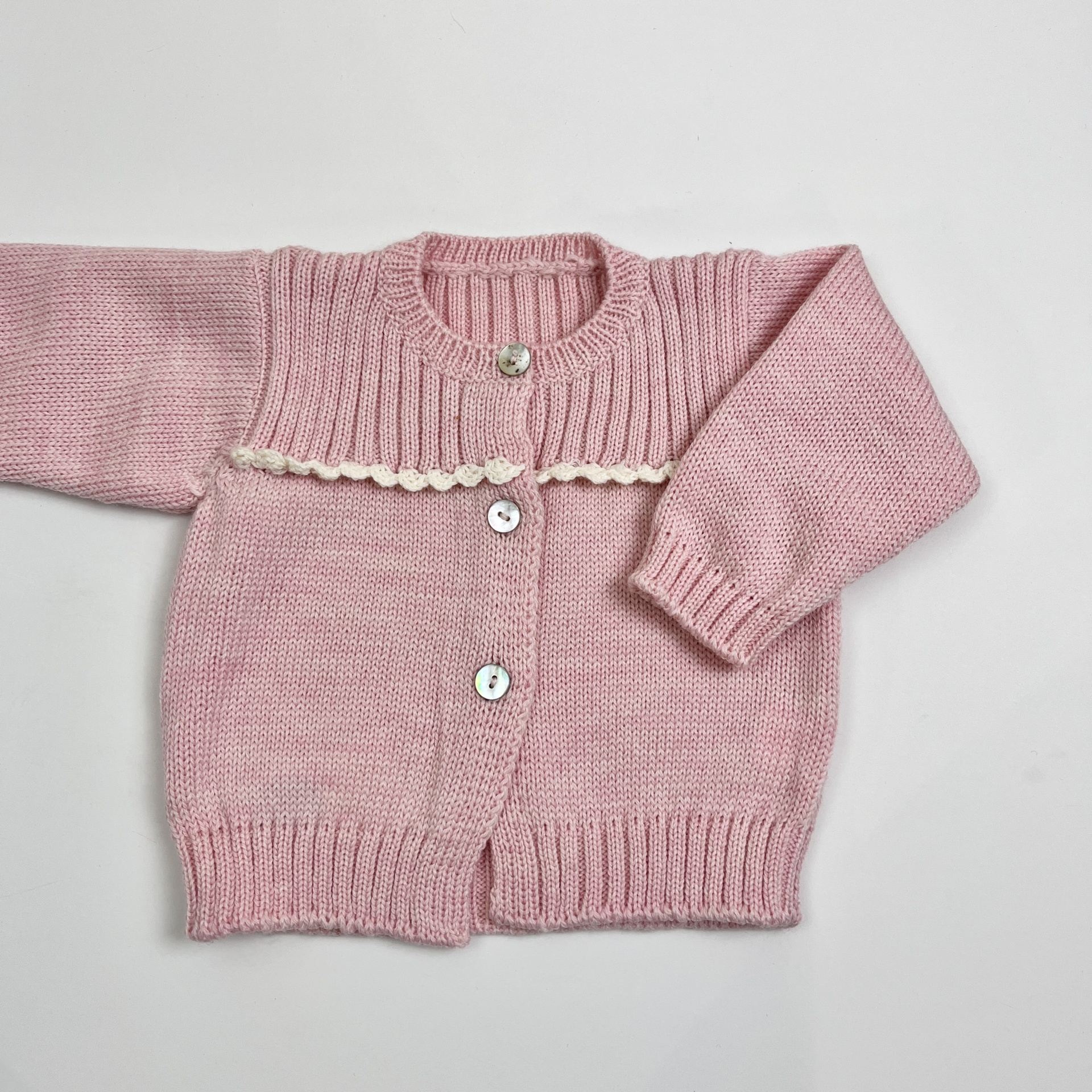 Casaco de malha cor-de-rosa para bebé com botões brancos e bordado creme.