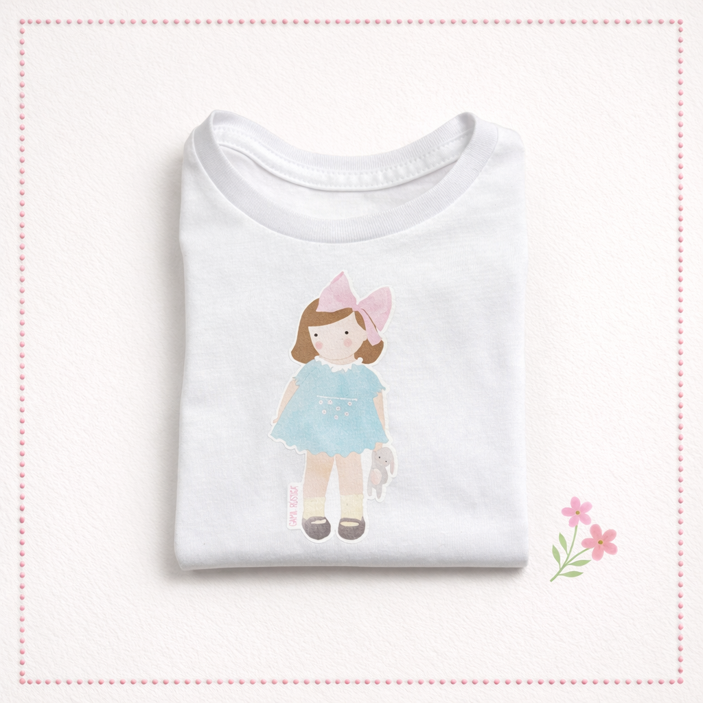 Camisola branca para criança com desenho de boneca e laço rosa.