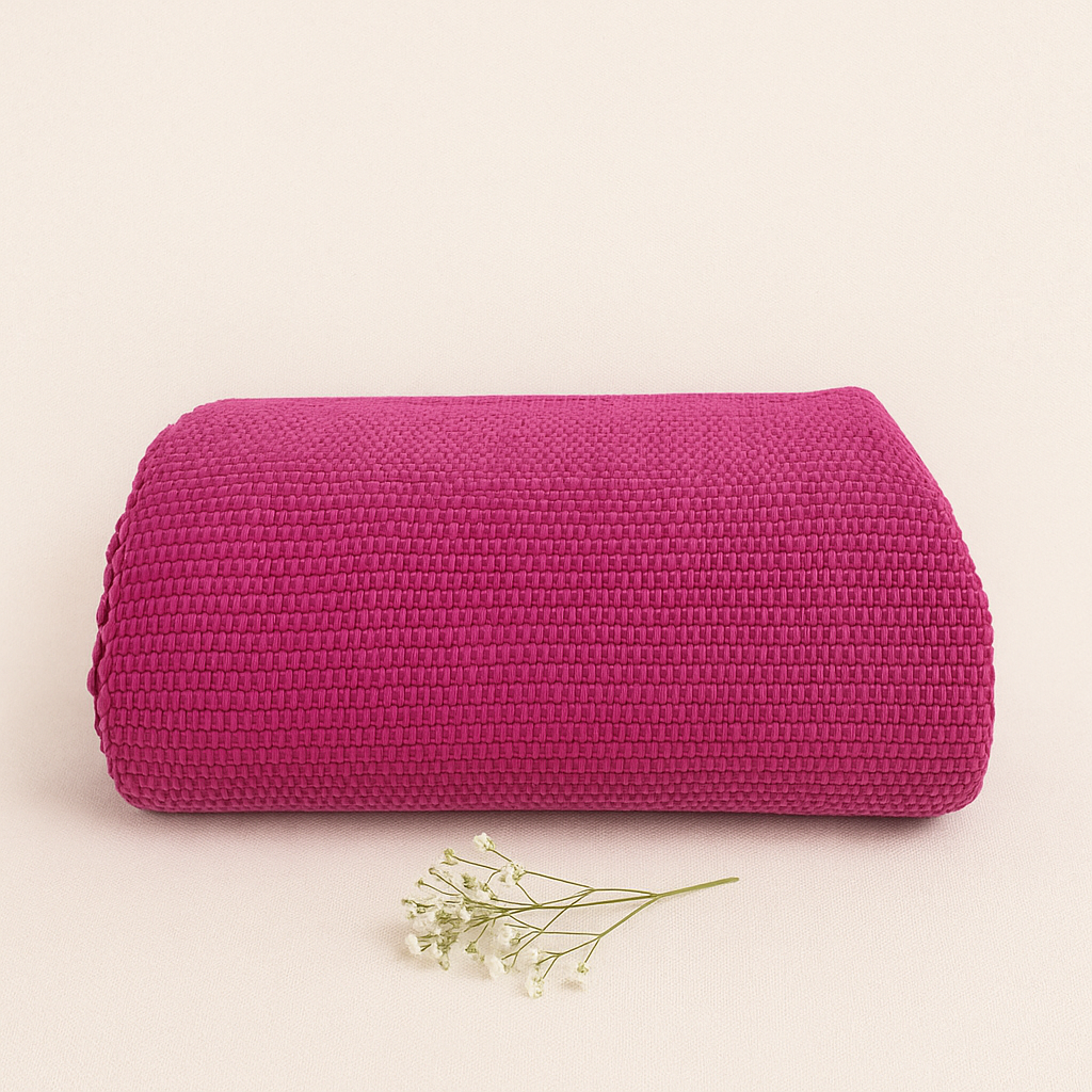 Manta rosa escuro texturizada enrolada com ramo de flores brancas secas