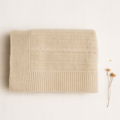 Manta bege claro com padrões de pontos, flores secas ao lado