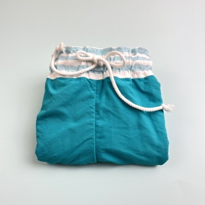 Calções de praia azuis com cintura elástica cinza e branca e cordão branco, dobrados