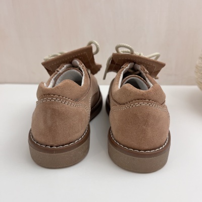 Sapatos de camurça castanha vistos de trás com cadarços brancos