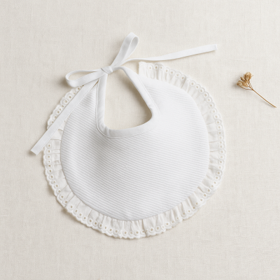 Babete branca redonda com renda e laço em fundo bege