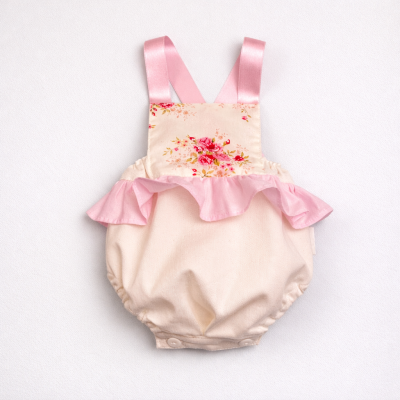 Roupa de bebé bege com alças rosas e folhos