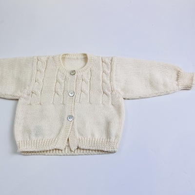 Camisola de bebé em malha creme com botões brancos e padrão de tranças