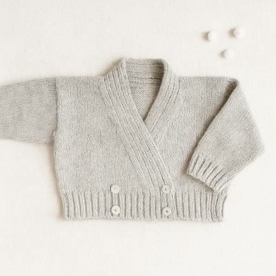 Casaco de malha cinzento claro para bebé com botões brancos e pompons ao lado
