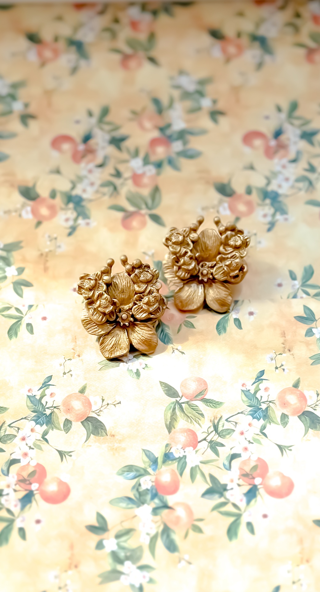 Luna Brincos dourados florais sobre fundo decorativo floral pastel