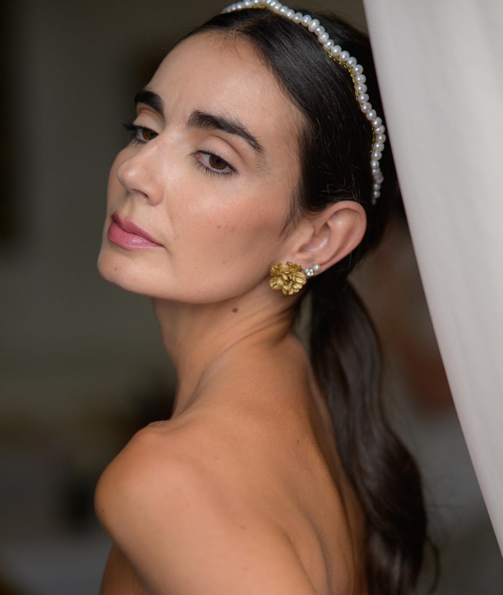 Ambrosis I Mulher com faixa de cabelo com pérolas e brincos dourados florais