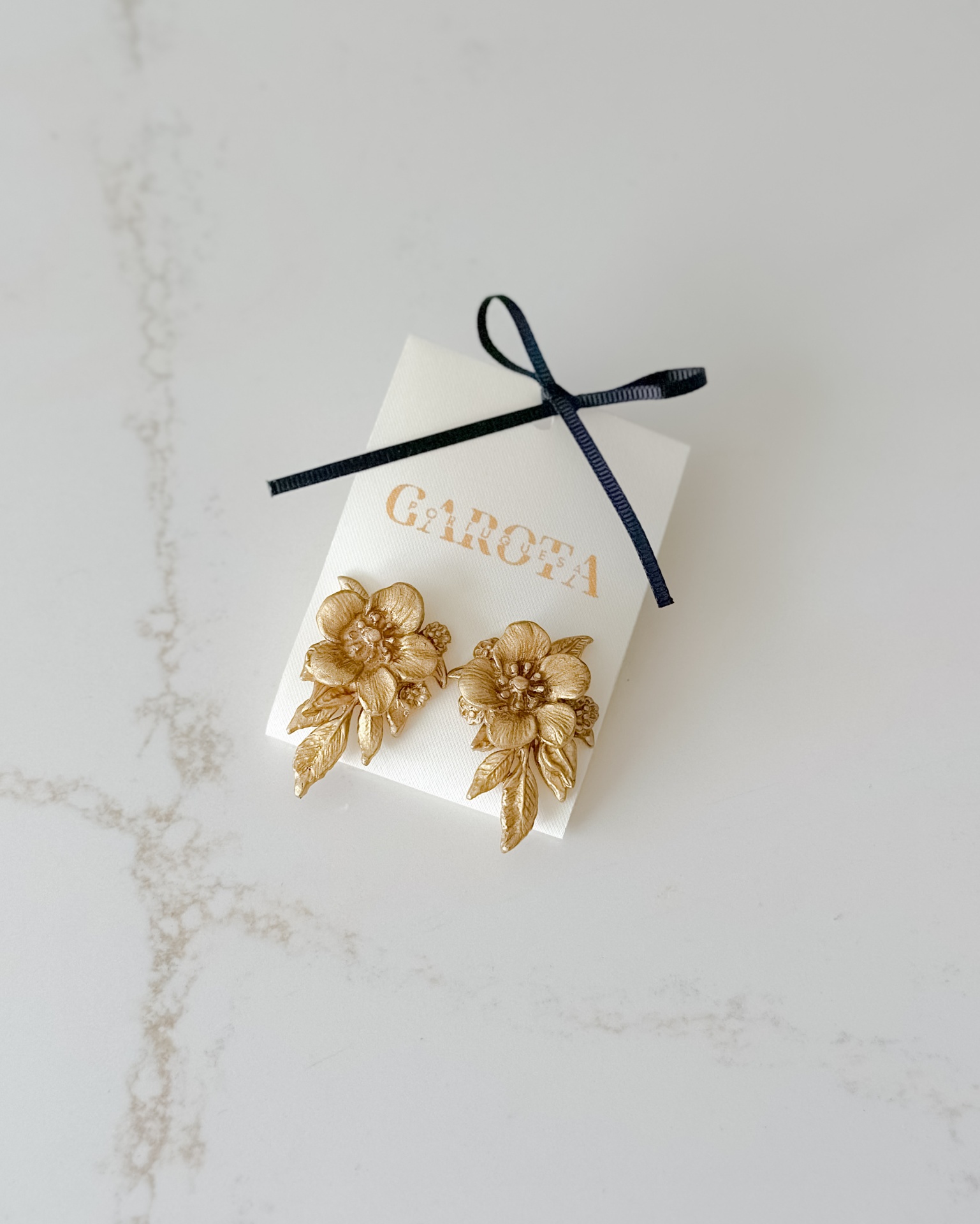 Bela II Brincos dourados em forma de flores detalhadas numa embalagem branca com laço preto