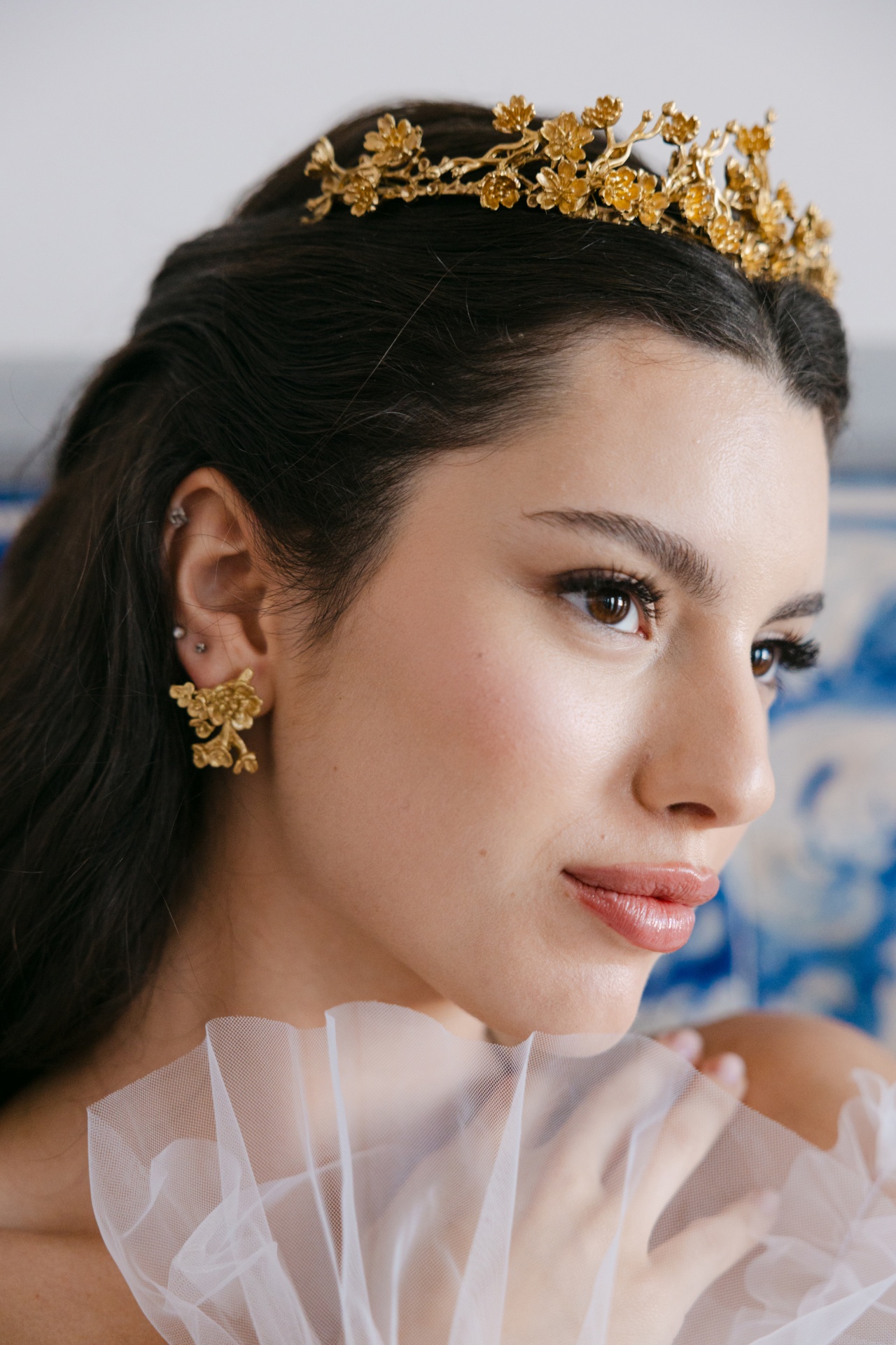 Venice I Mulher com tiara e brincos dourados florais e vestido branco com tecido translúcido