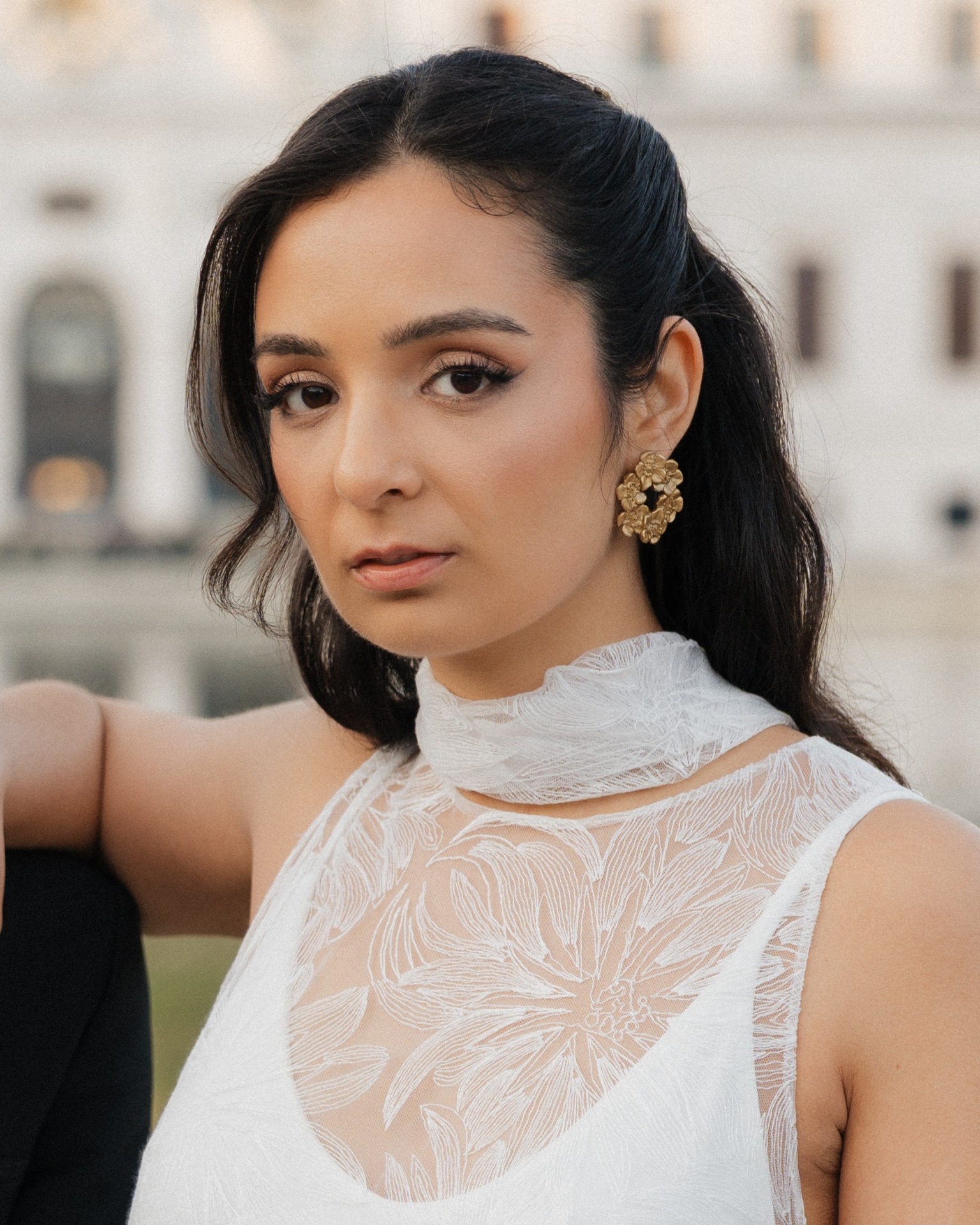 Floritta II Mulher com vestido branco de renda e brincos dourados grandes