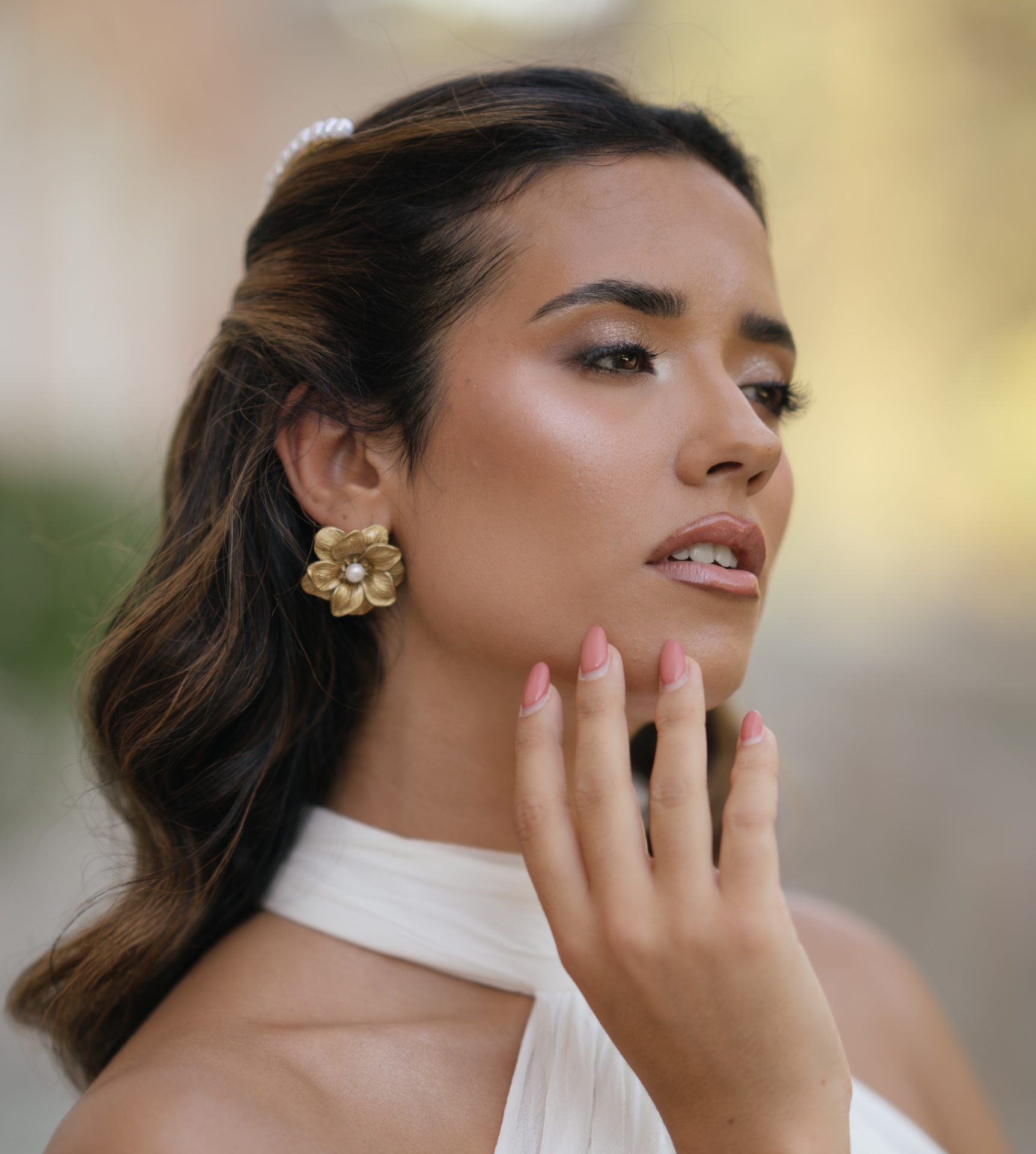 Passionata Brincos flor dourados com pérola no centro em mulher com cabelo castanho escuro e vestido branco