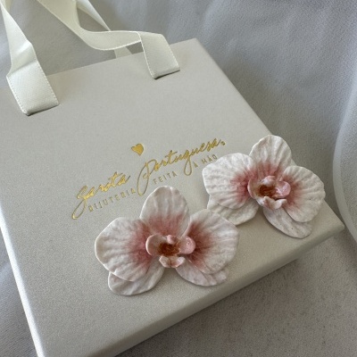 Embalagem creme clara com texto dourado e duas flores artificiais rosa e branca