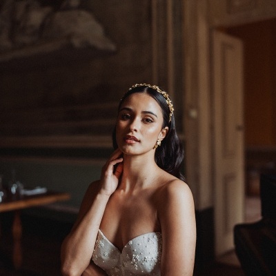 Vestido de noiva branco com pedrarias e tiara dourada em ambiente interior