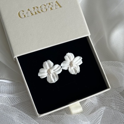 Brincos florais brancos em caixa branca de acessórios