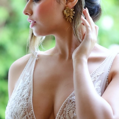 Mulher com brincos dourados florais e vestido branco de renda