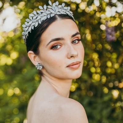 Mulher com tiara prateada de folhas e vestido branco ao ar livre