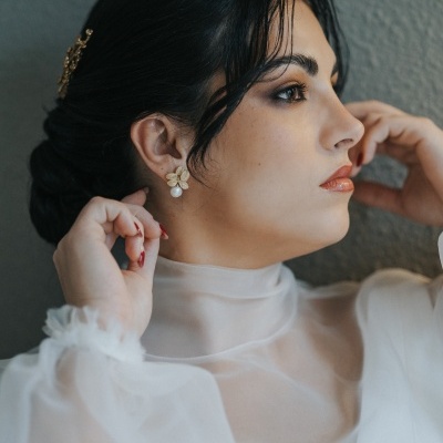 Mulher com vestido branco transparente e brincos florais com pérola