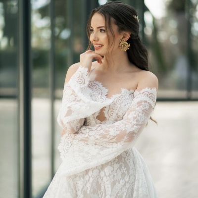 Mulher com vestido de noiva branco em renda, cabelo apanhado, em ambiente moderno com vidro