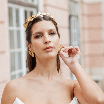 Modelo com vestido branco e acessórios dourados em forma de folhas