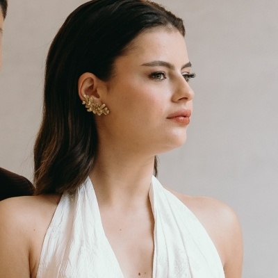 Mulher com vestido branco e brinco dourado decorativo em forma de folhas