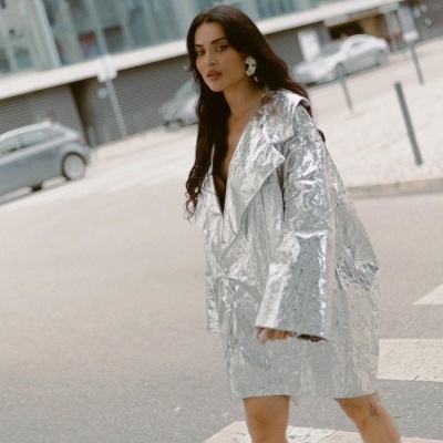 Casaco metálico prateado com textura enrugada numa modelo numa rua urbana