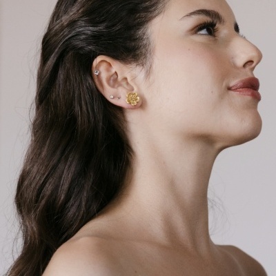 Mulher com tiara dourada floral e brincos dourados em perfil