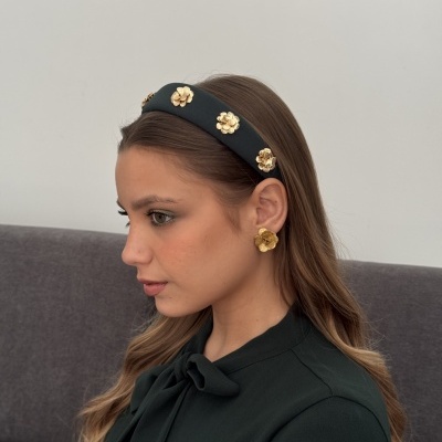 Mulher com faixa de cabelo preta com flores douradas e brincos em forma de flor dourada
