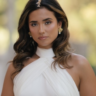 Mulher de vestido branco com acessórios dourados e pérolas.