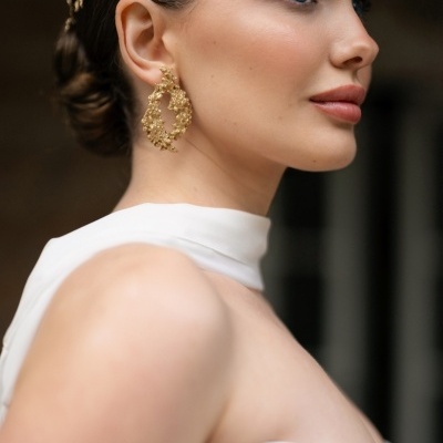 Mulher com vestido branco e acessórios dourados florais