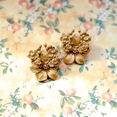 Brincos dourados florais sobre fundo decorativo floral pastel