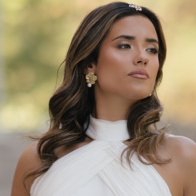 Mulher com vestido branco e brincos dourados com pérola