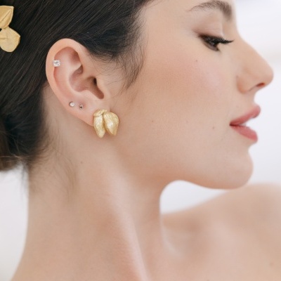 Mulher com brinco dourado e piercing na orelha