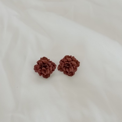 Brincos castanhos em forma de flor sobre fundo branco